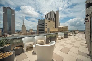 Eine Dachterrasse mit Sitzgelegenheiten im Freien, Topfpflanzen und Blick auf die Stadtlandschaft.