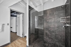 Un baño moderno con ducha, inodoro con cerramiento de vidrio y un perchero visible.