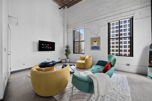 A modern living room with a sofa, armchair, and a television mounted on the wall. - Top-Floor Downtown Penthouse - Terrace - 2,500 Sq - Gym+Pool+Dedicated Workplace (Dallas)