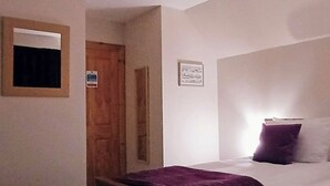 A bedroom with a bed, a door, and a wall-mounted picture frame.