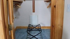 A narrow room with a blue carpet, a black metal drying rack, and wooden shelves. - Larchside Guest House  (Portree)