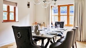 Ein Essbereich mit einem Holztisch, gedeckt für zwei Personen, ein schwarzer, mit Stoff bezogener Stuhl mit Ringlehne und ein grauer, mit Stoff bezogener Stuhl.