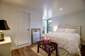 A bedroom with a bed, a nightstand, a lamp, a mirror, and a window. - Breezy, Bright 1 Bedroom Apartment 3 Blocks to Ledbetter Beach and Harbor (Santa Barbara)