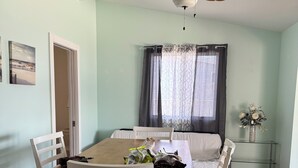 A dining area with a wooden table, white chairs, a ceiling fan, and a window with curtains. - Pop’s Place
Quaint Lagoon Front Home 3 minutes to LBI. (Stafford Township)
