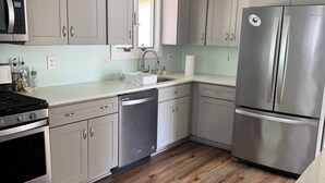 A kitchen with grey cabinets, stainless steel appliances, a dishwasher, and a wooden floor. - Pop’s Place
Quaint Lagoon Front Home 3 minutes to LBI. (Stafford Township)