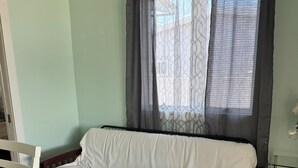 A room with a wooden floor, a white sofa, a small table, and a window with curtains. - Pop’s Place
Quaint Lagoon Front Home 3 minutes to LBI. (Stafford Township)