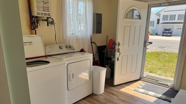 A compact laundry room with a washer and dryer, a door leading outside, and a window with curtains. - Pop’s Place
Quaint Lagoon Front Home 3 minutes to LBI. (Stafford Township)