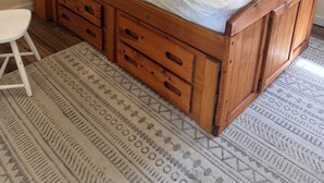 A wooden bed with storage drawers and a headboard, a white chair, and a patterned rug in a room with plain walls. - Pop’s Place
Quaint Lagoon Front Home 3 minutes to LBI. (Stafford Township)