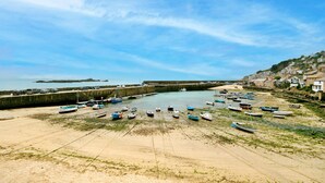 Ein Küstenort mit Sandstrand, einem Hafen voller Boote und einer Steinmauer.