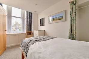 A bedroom with a bed, a window, a desk, and a framed picture on the wall. - Grand Devon Country House for 15 (Penzance)