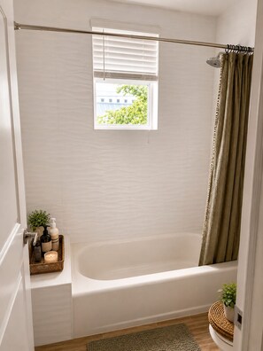A bathroom with a bathtub, a window, a shower curtain, and a small window with blinds. - Bright Modern Room w/ Balcony Access (Miami)