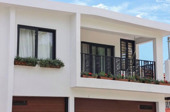 Un bâtiment moderne à deux étages, doté d’un balcon, de grandes fenêtres et d’une porte de garage.