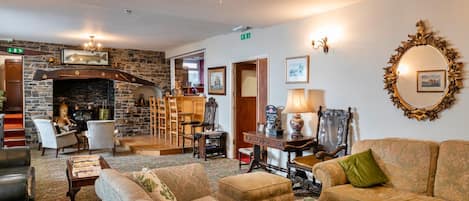 A cozy hotel lobby with a fireplace, comfortable seating, and a chandelier.
