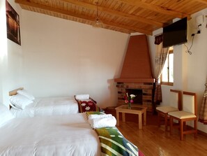 A room with two beds, a fireplace, a television, and a window with curtains. - Brisas Del Lago San Pablo (Otavalo)