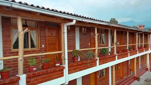 A two-story building with multiple windows and balconies, each with potted plants. - Brisas Del Lago San Pablo (Otavalo)