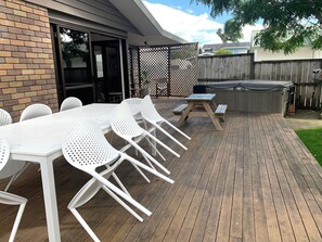 Une terrasse extérieure avec une plateforme en bois, des chaises en plastique blanches et une table de pique-nique.