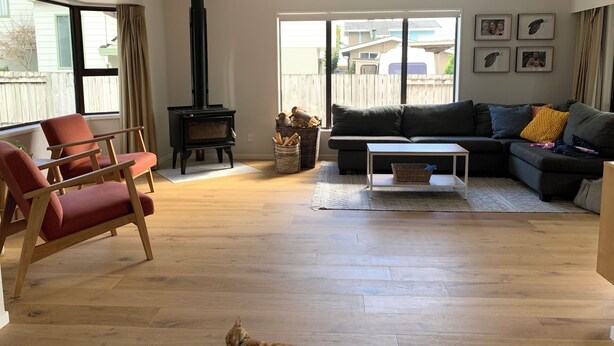 A living room with a sofa, armchair, and a fireplace. - Relaxing haven for Families - minutes walk to the beach, shops & dining (Tauranga)