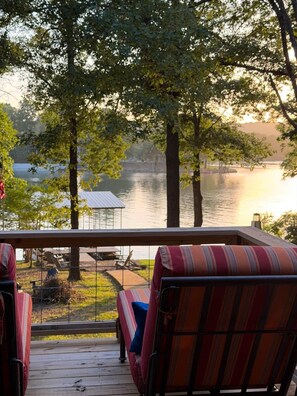 Eine Terrasse mit Stühlen, die auf einen stillen See mit Baumumrandung blickt.