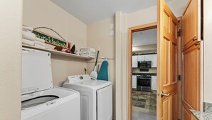 A laundry area with a washing machine, dryer, and ironing board. - Walk to Peak 9, Quicksilver Lift & Main St - Private Hot Tub & Garage (Breckenridge)