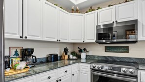 A kitchen with white cabinets, a microwave, a toaster, a coffee maker, and a stove. - Walk to Peak 9, Quicksilver Lift & Main St - Private Hot Tub & Garage (Breckenridge)