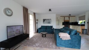 A living room with a sofa, a coffee table, and a television. - Stylish Waterfront Villa With Sauna (Makkum)