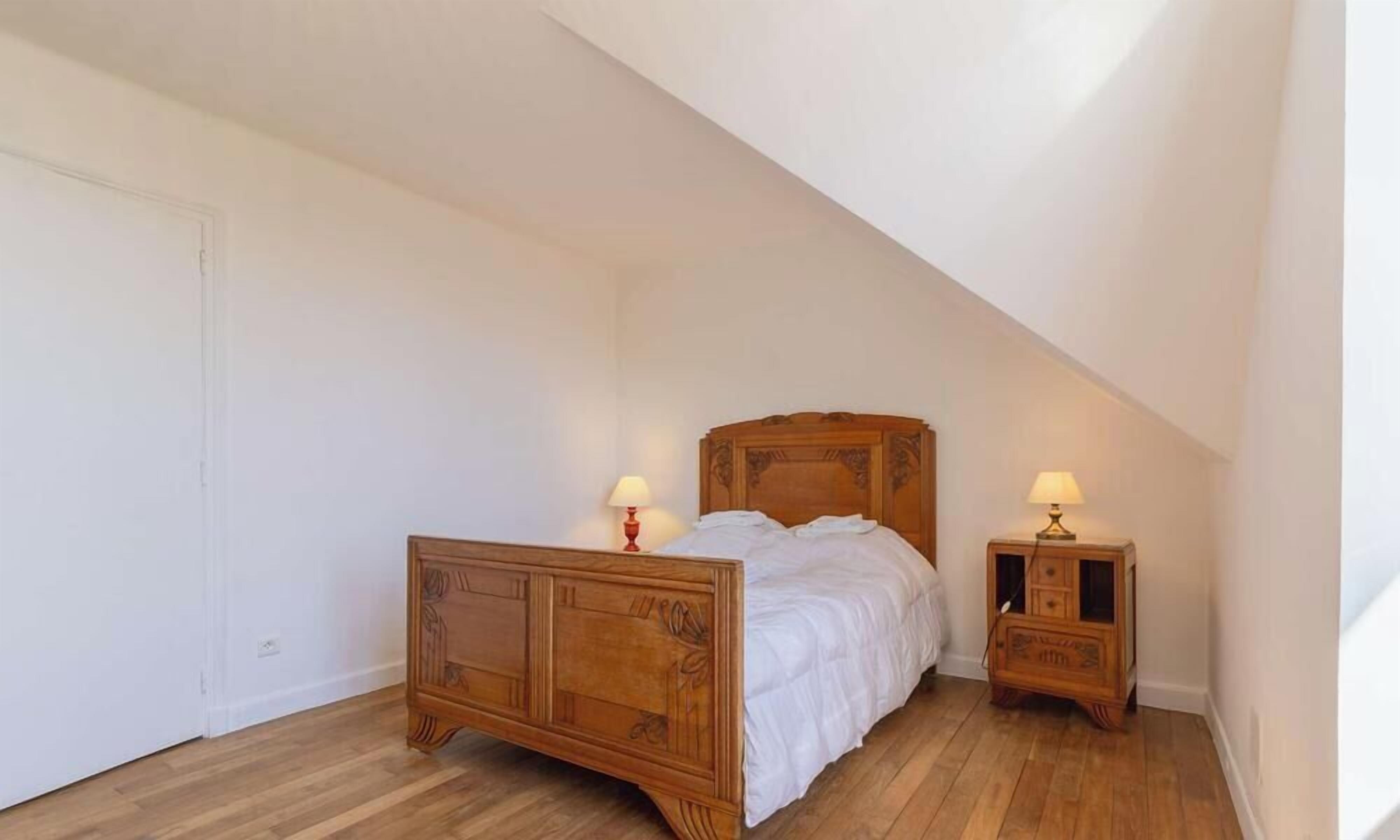 Una camera da letto con un letto in legno, due comodini con lampade e una porta bianca.