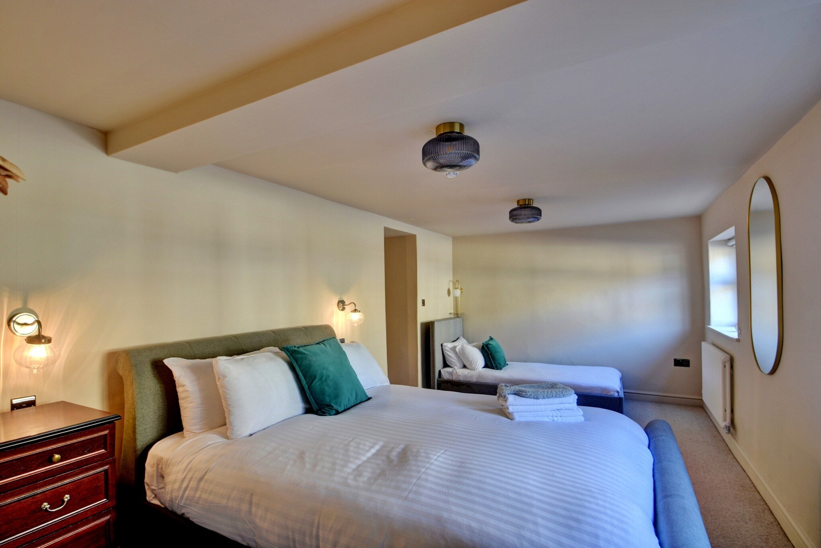 A hotel room with a large bed, a smaller bed, a dresser, and a mirror.