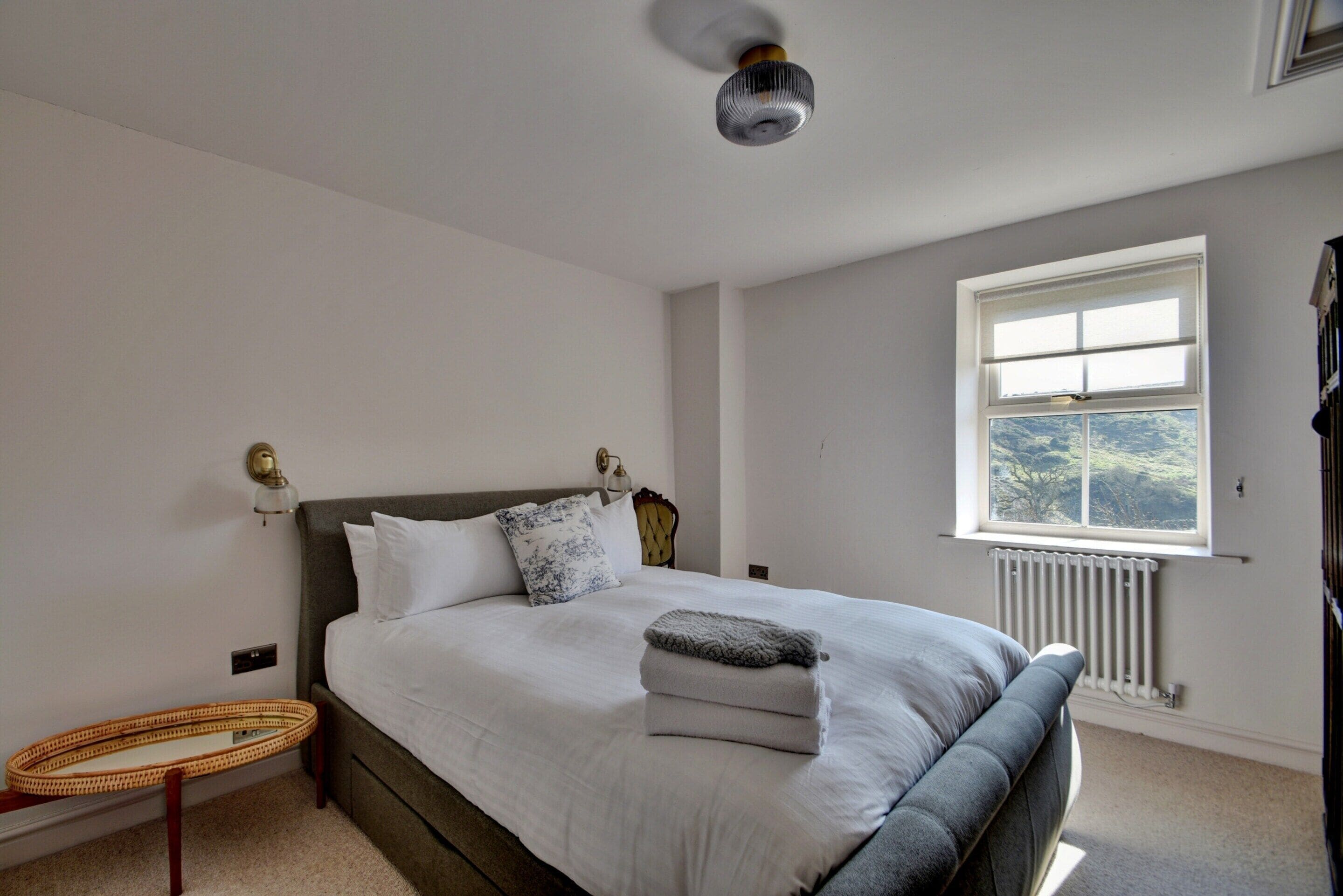 Une chambre à coucher avec un lit, une lampe de chevet, une fenêtre et un radiateur.