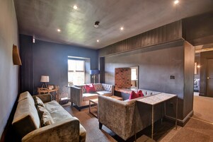 Una sala moderna con un sofá seccional, una mesa de centro y una chimenea.