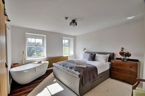 Ein Schlafzimmer mit einem großen Bett, einer Badewanne und einer Kommode.