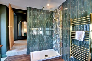 Ein modernes Badezimmer mit einer Duschkabine aus Glas, einer weißen Badewanne und einem goldenen Handtuchhalter.