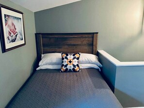 A single bed with a headboard, white pillows, and a patterned throw pillow. - The Cabin at 114 Main Street with Hot Tub (Augusta)