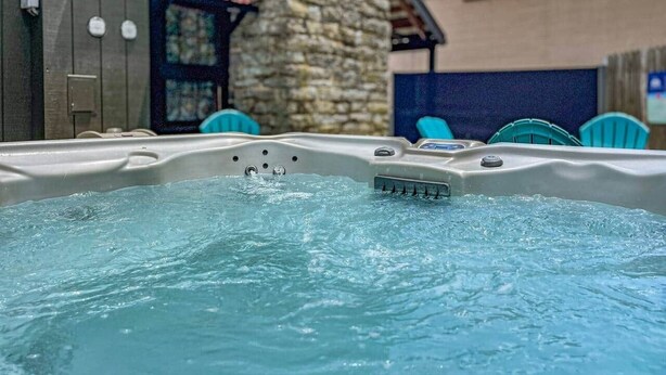 Un jacuzzi con chorros de agua, rodeado de muros de piedra y mobiliario para exterior.