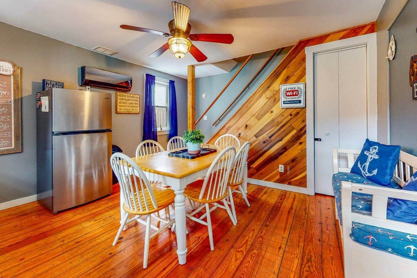A compact kitchen with a refrigerator, dining table, and chairs.