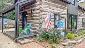 A log cabin with a porch, a flag, and a sign for a rental business.