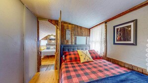 Ein Schlafzimmer mit einem Bett, einem Kopfteil, einem Fenster mit Vorhängen und einem Wandbild.