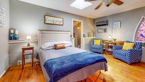 Un dormitorio con cama, una silla, una mesa y un ventilador de techo.