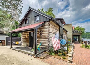 Une cabane en rondins avec un porche, un drapeau américain et une enseigne indiquant qu’il s’agit d’un bureau.