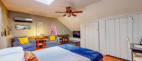 A bedroom with a bed, a desk, a chair, a wardrobe, a ceiling fan, and a skylight.