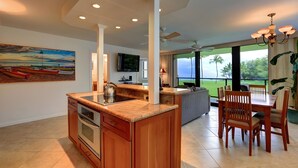 Uma cozinha moderna com uma ilha central, um espaço de refeições com cadeiras de madeira e uma grande janela com vista para o exterior.