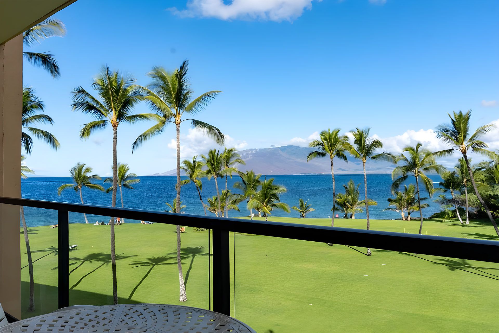 A balcony with a view of a golf course and the ocean.