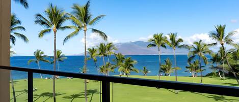 A balcony with a view of a golf course and the ocean.