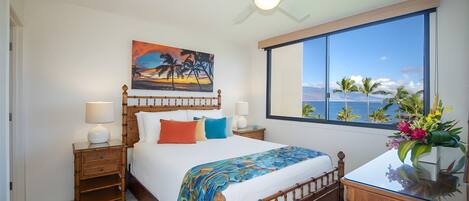 Una habitación de hotel con cama, un cuadro, una ventana con vistas y un ventilador de techo.
