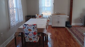 A room with a bed, a small table, a cabinet, and a window with curtains. - Newly renovated, New England 3-bedroom home in Skowhegan. (Skowhegan)