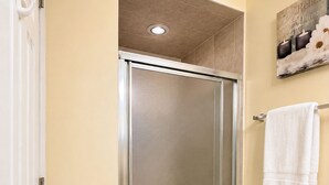 Ein Badezimmer mit Duschabtrennung aus Glas, einem weißen Handtuchhalter und einem weißen Handtuch an der Wand.