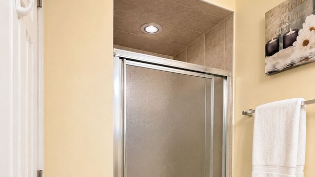 A bathroom with a glass shower door, a white towel rack, and a white towel on the wall.