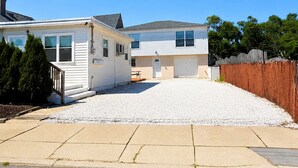 A two-story house with a covered patio and a gravel driveway.