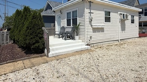 A single-story mobile home with a front porch, a small deck, and a potted plant.