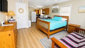 A compact bedroom with a bed, a desk, a chair, a wardrobe, a television, and a ceiling fan.