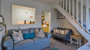 A living room with two grey sofas, a small wooden table, and a staircase with white railings. - 19th Century Cottage Near Brixham Harbour (Brixham)